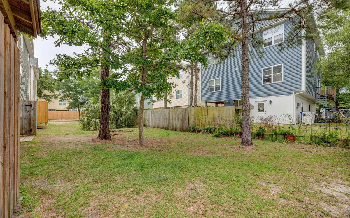 This image shows a tranquil, fenced yard with lush trees and the back of the house visible. The green space offers plenty of room for pets to play and relax, while the fence provides safety and privacy.