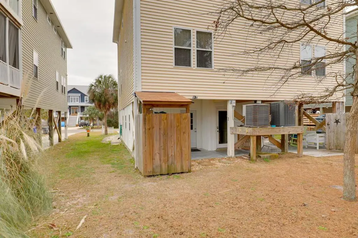The exterior of the property is shown with a welcoming side entrance, a wooden shed, and surrounding greenery. The image hints at outdoor spaces for gathering and relaxing just steps from the front door.